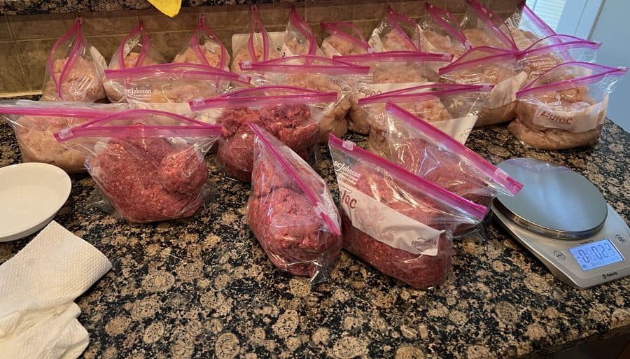A counter covered in portioned bags of raw ground meat for the week, next to a digital food scale