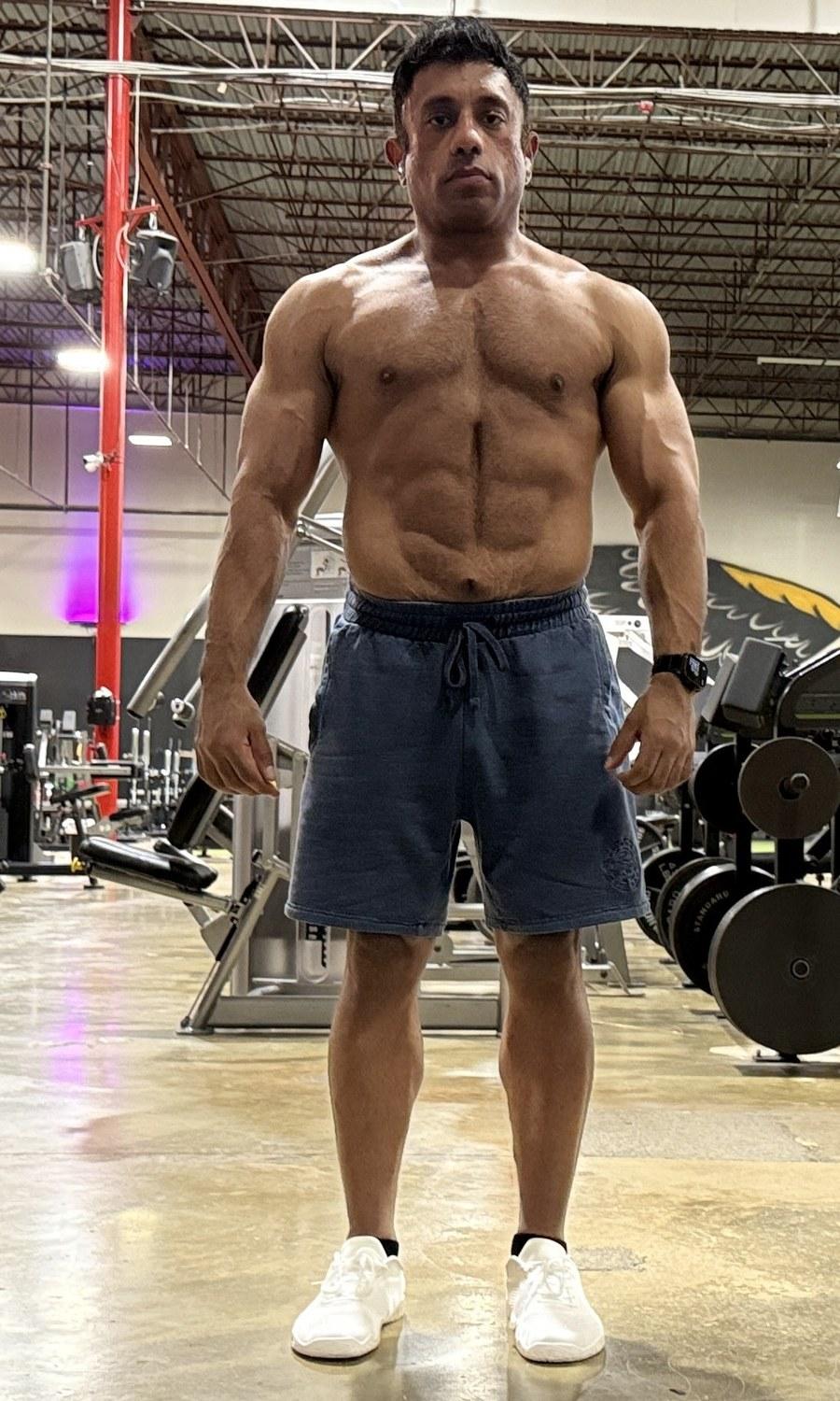 Hammad standing shirtless in a bright gym, facing the camera