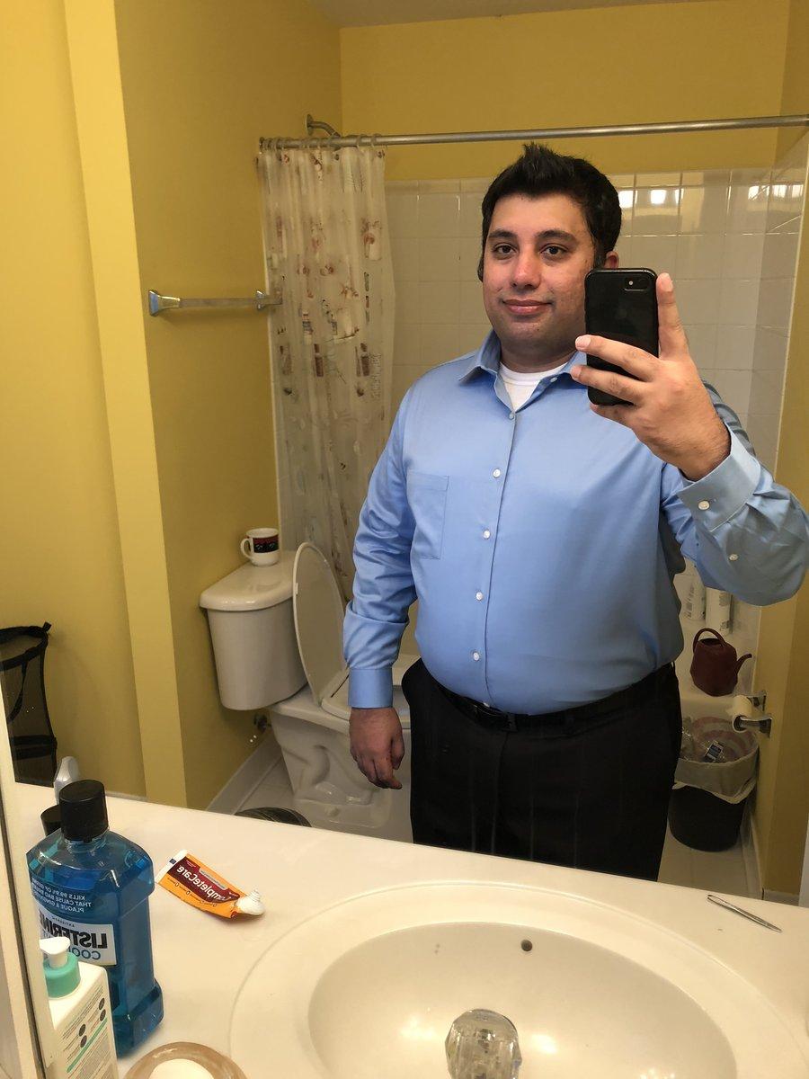 Hammad in January 2019, bathroom mirror selfie in a tucked light-blue dress shirt, visibly heavy
