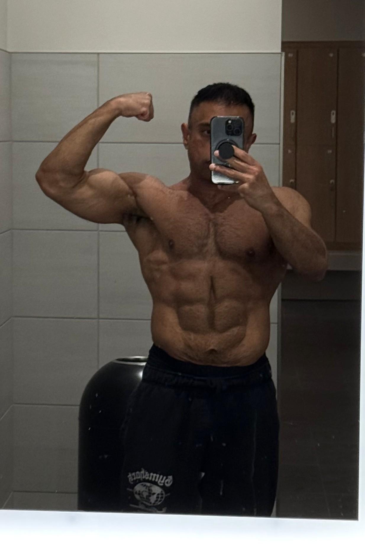 Hammad at 40 in September 2026, shirtless gym mirror selfie flexing, with visible abs