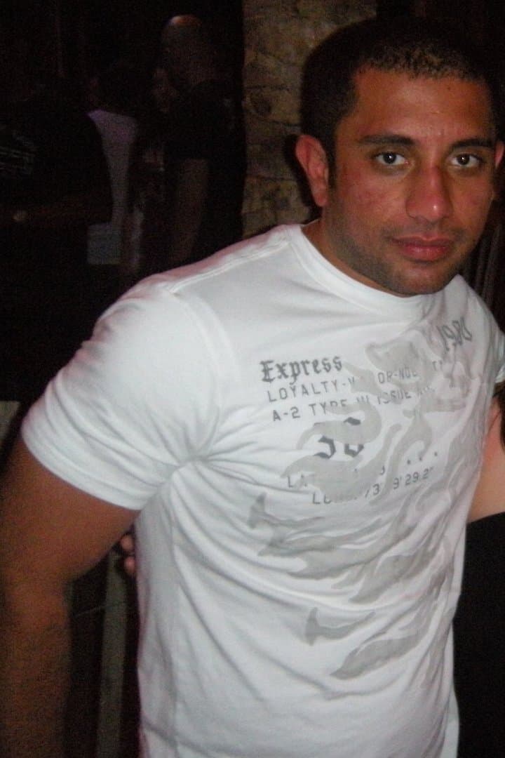 Hammad in his twenties at a night out, in a fitted white t-shirt, noticeably leaner